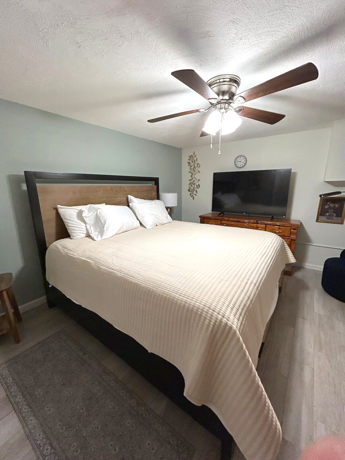 King suite with sage green accent wall and smart TV